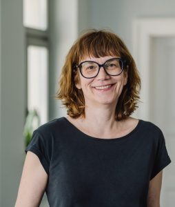 Junge Frau mit braunen Locken und Brille